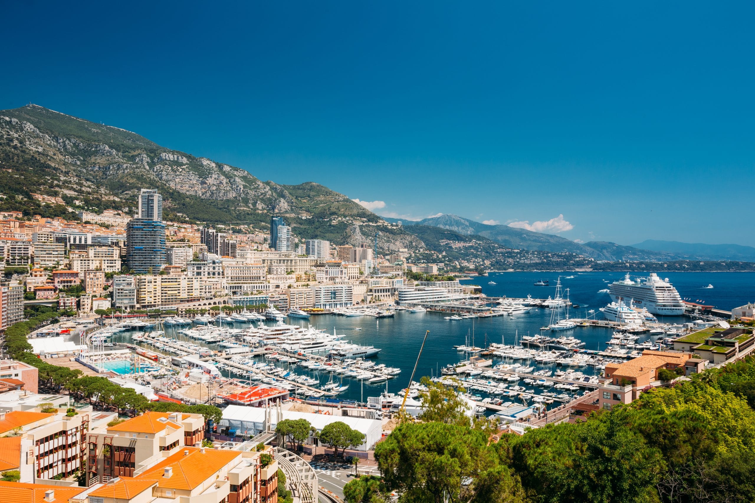 Monaco, paesaggio urbano di Montecarlo. Architettura immobiliare su sfondo di collina. Molti grattacieli nel centro città. Yacht ormeggiati al molo della città in una soleggiata giornata estiva.